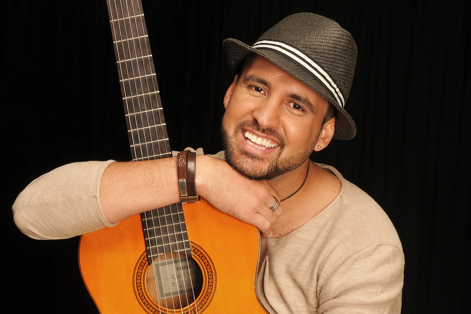 Alessandro Galas lächelt, auf seine Gitarre gestützt