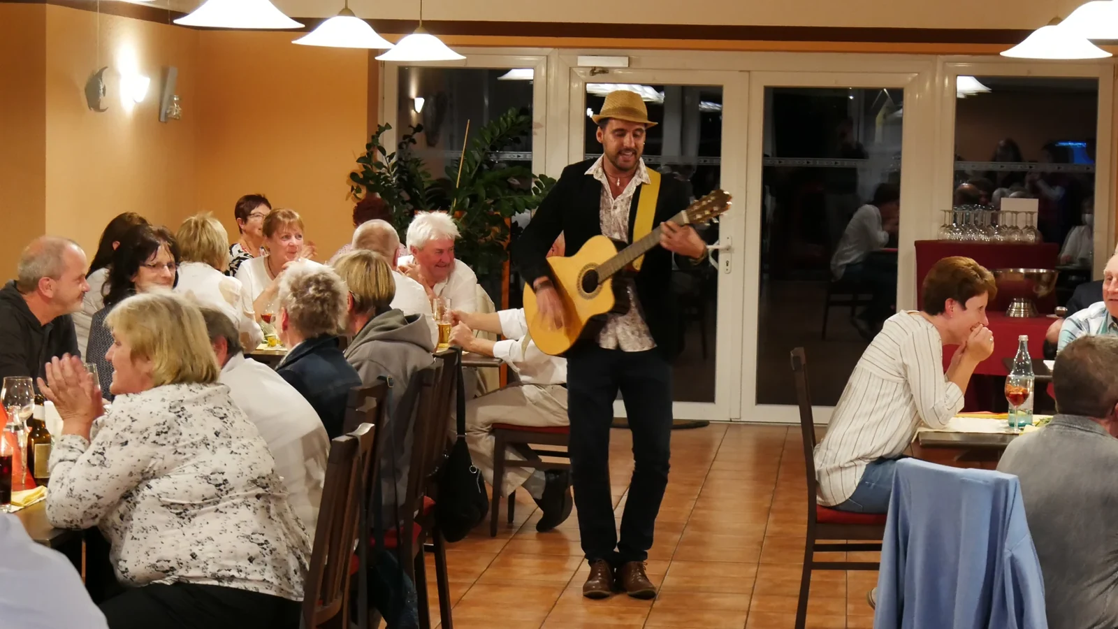 Alessandro Galas spielt Gitarre im Kreis der Gäste einer Feier